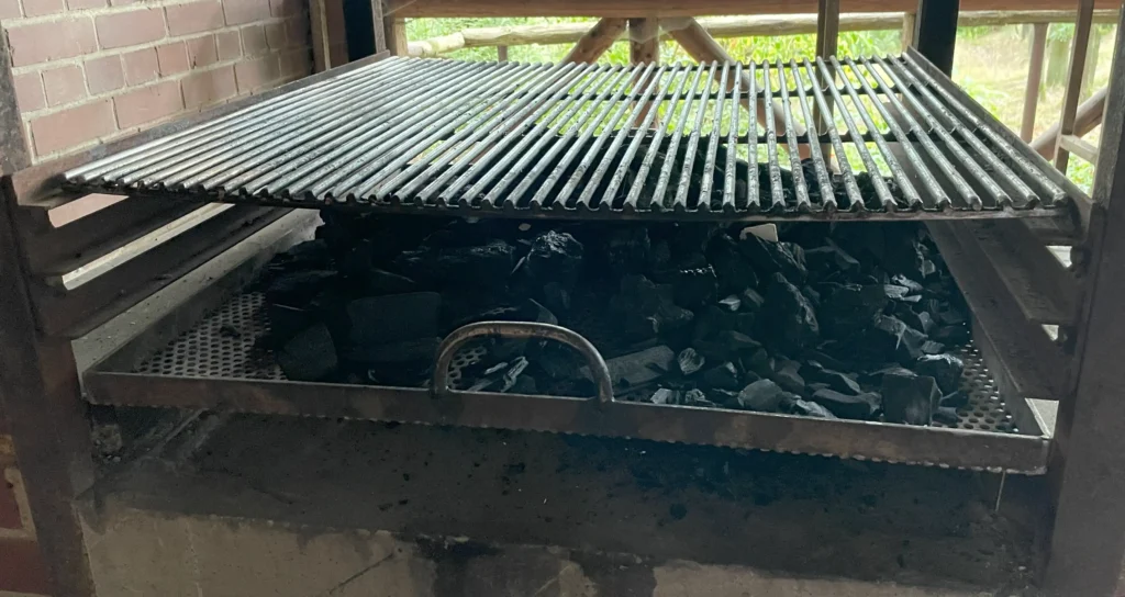 Zwei Roste in einem Grill, auf dem unteren Rost liegt Asche
